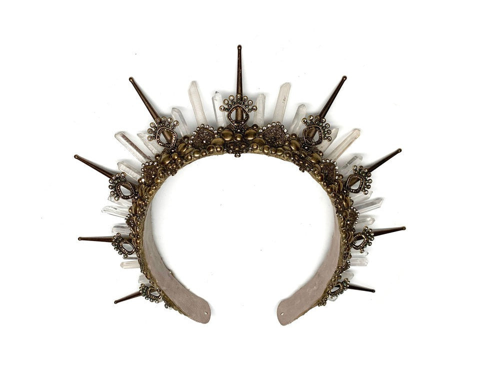 Inspired by the Egyptian goddess of Mystery, this antique gold headpiece turns heads with 3 inch spikes and cascading quartz crystals. The geometric filigree sparkles with authentic black and peacock green pearls, as well as gold and natural rhinestones for an extra goddess glimmer.